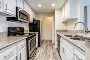 granite countertops, stainless steel appliances and wood floors in the kitchen