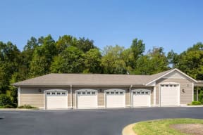 building with five covered and enclosed parking garages with tan siding and white garage doors