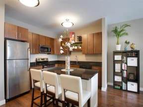 Be @ Axon Green  Apartment Kitchen with Wood Cabinets, Black Granite Island, and Stainless-Steel Appliances