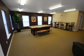 Billiards table with dark brown wall along back and 3 windows, tan wall to right.