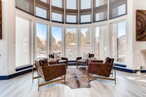 Denver Apartments for Rent - Allure - Clubhouse with Lots of Windows, Four Leather Chairs, and Bear Skin Rug
