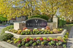 a sign for villaggio on ardennes boulevard with flowers in front of it