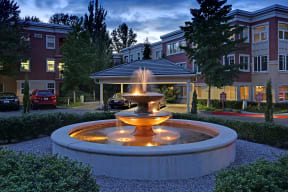 a fountain in front of a building at dusk