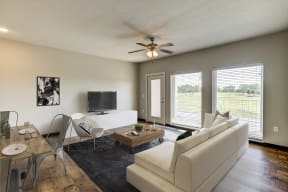 Apartments in Lawrence - Fairway Flats - Spacious Living Area with Large Windows, Wood Flooring, Ceiling Fan, and White Walls