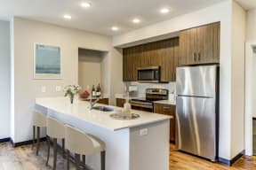 Apartments for Rent in Lawrence KS - Fairway Flats - Modern Kitchen with White Countertops, Wooden Cabinets, and Stainless Steel Appliances