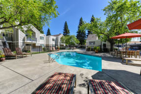 Pool Area with Trees, Red/White/Black Lines Runing Down Lounge Chairs and Apartment Exteriors