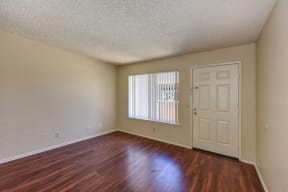 Empty Living Room with Hardwood Inspired Floors, Window and White Door