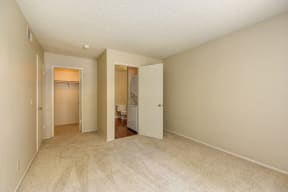 Empty Bedroom with Carpet, Open Bathroom Door, and Closet