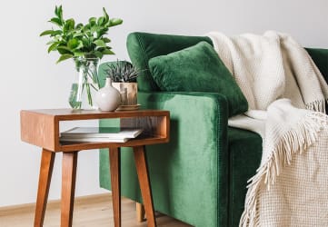 Green sofa with side table and plant