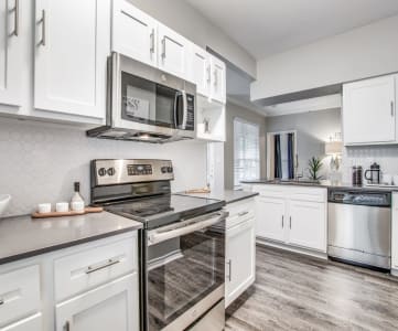 North Dallas TX Apartments- Spacious Modern Kitchen With Gray Granite Countertops, White Cabinets, and Stainless Steel Appliances