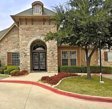 Building exterior with hedges and trees at The Life at Westland Estates, Texas, 76108