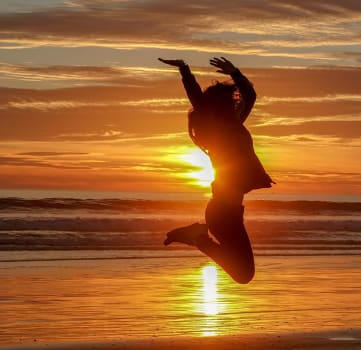 Girl jumping on beach in sunset 