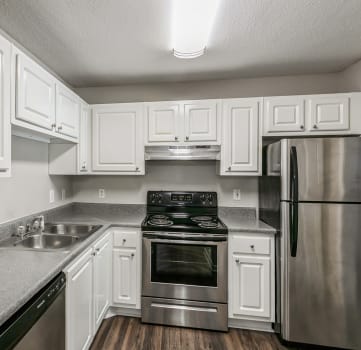 Remodeled kitchen with hardwood floors, white cabinets, stainless steel appliances including dishwasher, stove, and fridge