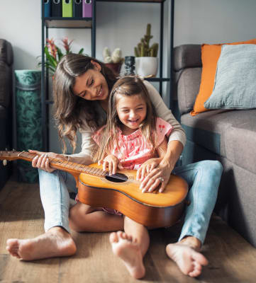 Mother and daughter playing guitar on apartment floor  at Arrive Los Carneros II, Goleta