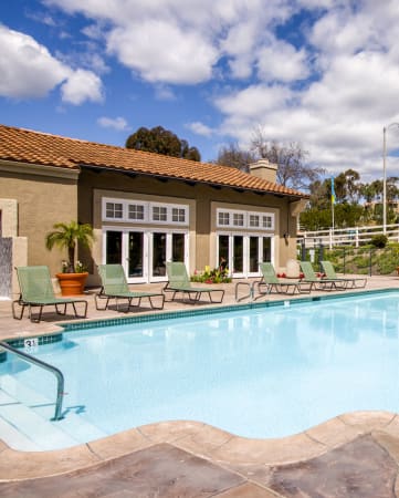 Carlsbad Apartments for Rent-Santa Fe Ranch Gated Pool With Lounge Chairs And Surrounding Brown Stone
