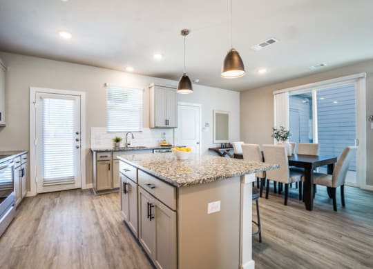 Canvas at Denton spacious kitchen with hardwood style flooring stainless steel appliances large island and granite countertops, build to rent, homes for rent in Denton, professionally managed rental home community, private yards, low maintenance, pet-friendly.
