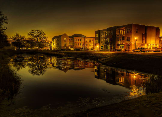 Evening photo of apartment buildings and pond at Link Apartments® Mixson, North Charleston