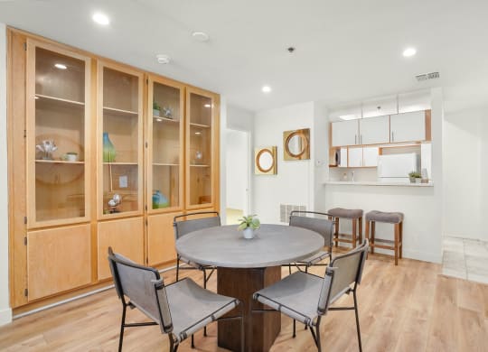 Apartment dining room area with a circular table with four chairs and built-in cabinets.
