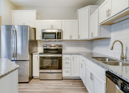 Kitchen with stainless steel appliances, light granite countertops, and while cabinetry at Cascade Pines Duplex and Townhomes