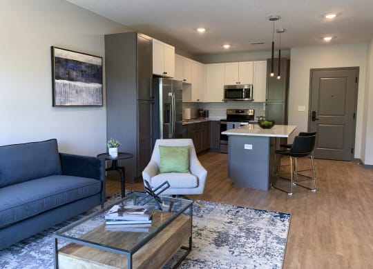 Furnished open concept living room looking into large kitchen in Bliss floor plan at Haven at Uptown in Lincoln.