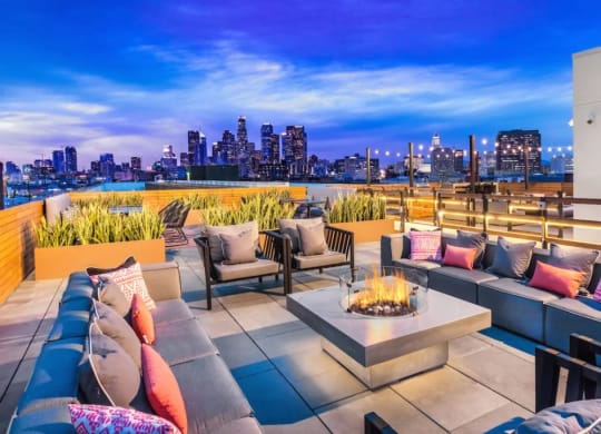 Apartment complex rooftop lounge area with fire pit and DTLA night view