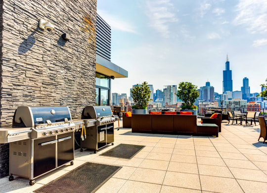 Outdoor grilling area with lounge seating and a skyline view at The Madison at Racine, Chicago, 60607