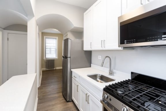 Kitchen with hardwood floors, stove, microwave and sink at Shorewind Apartments, Chicago, IL, 60649