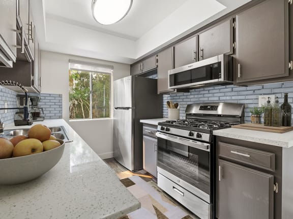 Tiled kitchen with stainless steel oven, microwave, and fridge.