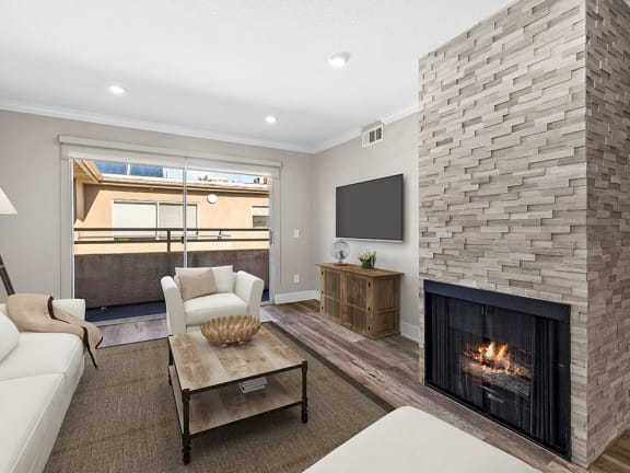 Living room with stone accented fireplace and balcony access.