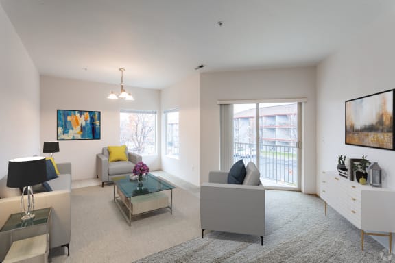 Spacious living room filled with light. Sliding glass door to private balcony. Staged with a couch, 2 chairs, table.