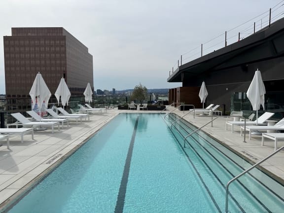 a swimming pool on the roof of a building with white lounge chairs and umbrellas