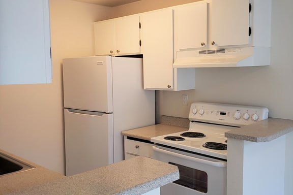 Apartments for Rent Des Moines - Marina Club - Kitchen With Beige Countertops, White Cabinets, and With an Electric Stove and Refrigerator