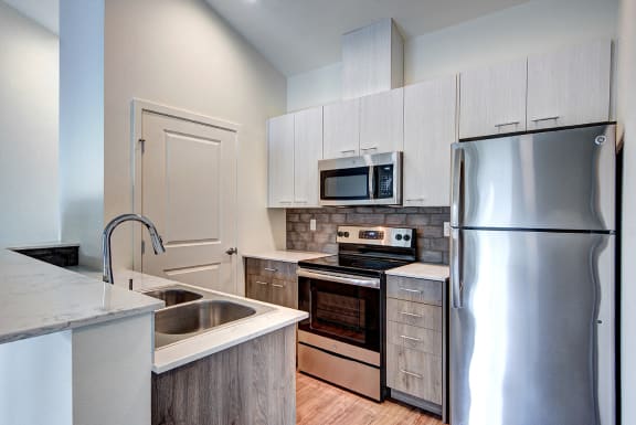 Apartments for Rent in Lynnwood - Beautiful Kitchen with Gray Cabinets, Stainless Steel Appliances, and Wood Flooring