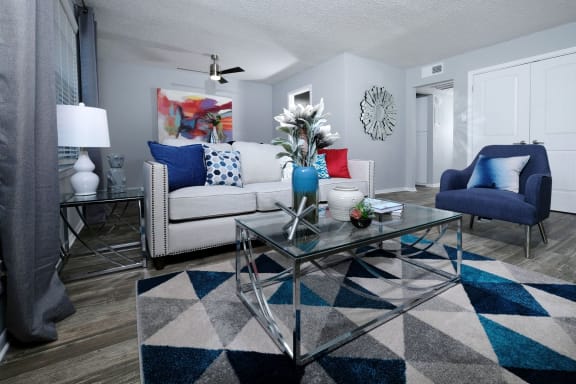 Apartments for Rent in Arlington TX - Stadium 700 - Spacious Living Room with Hardwood-Inspired Flooring, Light Grey Walls, Large Window, and a Ceiling Fan