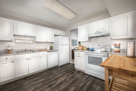kitchen at Vistas of Annandale apartments in Annandale, VA with laminated floor, white cabinets and appliances, and a wood table