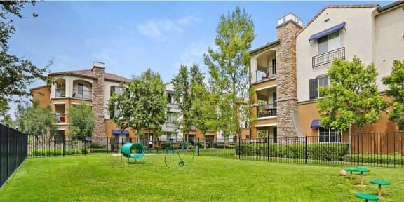 Pet-Friendly Apartments in Rancho Cucamonga CA - The Angelica - Outdoor Dog Park with Jumping Rings and Grass in Front of Building