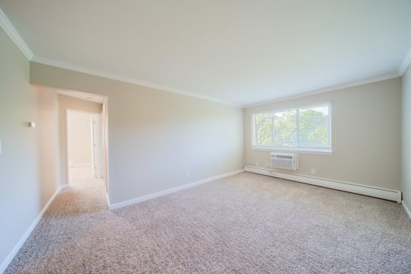 Living room with window and carpeting leading to hallway