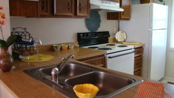 Kitchen with brown counter, brown cabinets, a stainless steal sink, and a white stove.