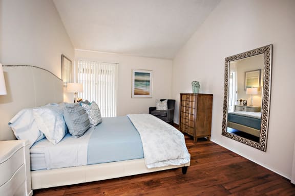 Oakview upstairs bedroom has vaulted ceilings, a closet, window with vertical blinds and most units have carpet in the bedroom.