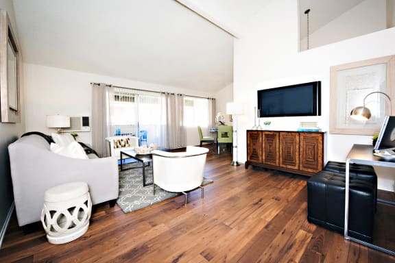 Oakview's upstairs apartment living room area has vaulted ceilings, with either wood vinyl flooring or carpet. The walls are while and has a patio sliding door leading to a patio..
