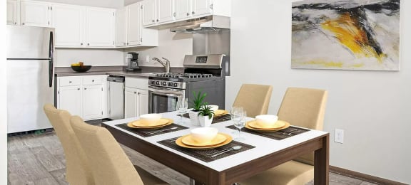 Modern white cabinet kitchen with stainless steel appliances and casual dining area with yellow chairs.