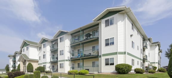 Exterior photo of The Legacy Apartments featuring patios, balconies, and outdoor green space.