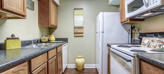 Kitchen with hardwood like flooring and white appliances