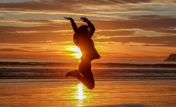 Girl jumping on beach in sunset 