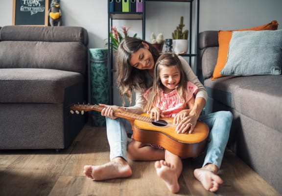 Mother and daughter playing guitar on apartment floor