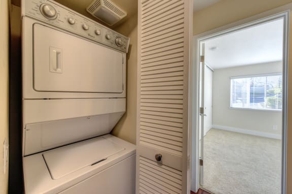 Full Sized stackable washer and dryer inside a closet with acordian style door. Washer/dryer closet location is just outside of bedroom.