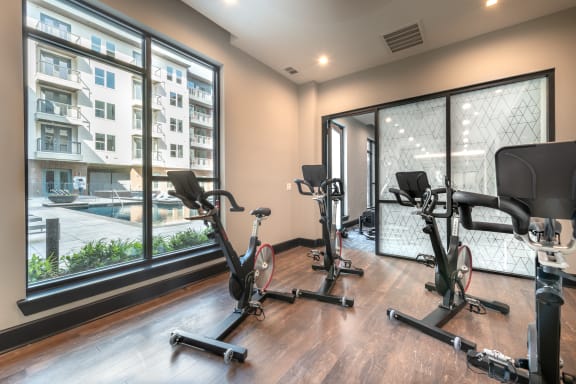 Gym area with multiple cardio bikes and a window with view of the pool