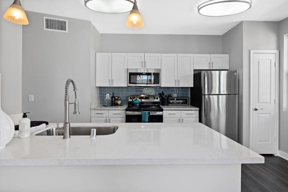 White kitchen with tile back splash and appliances l Apartments For Rent in Slymar CA at Rockwood at the Cascades