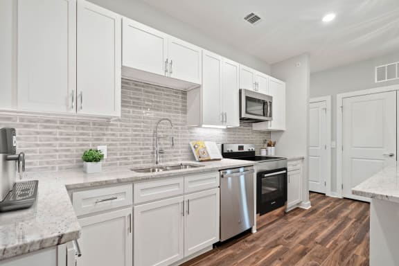 Beautiful white kitchen cabinetry, stainless steel appliances, tile backsplash and ceramic cooktop stove