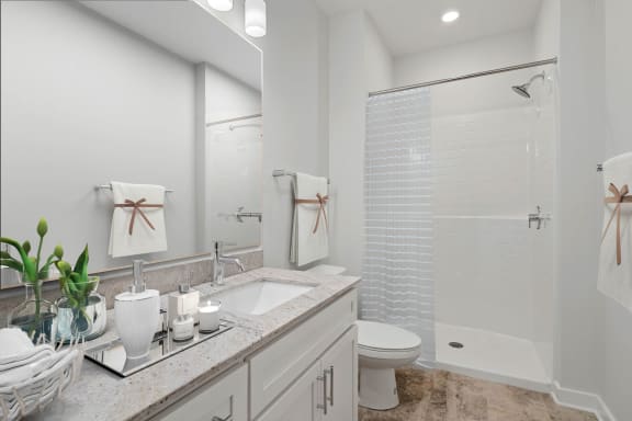 Spacious bathroom with designer lighting, a walk-in shower, spacious vanity and wood-finish flooring